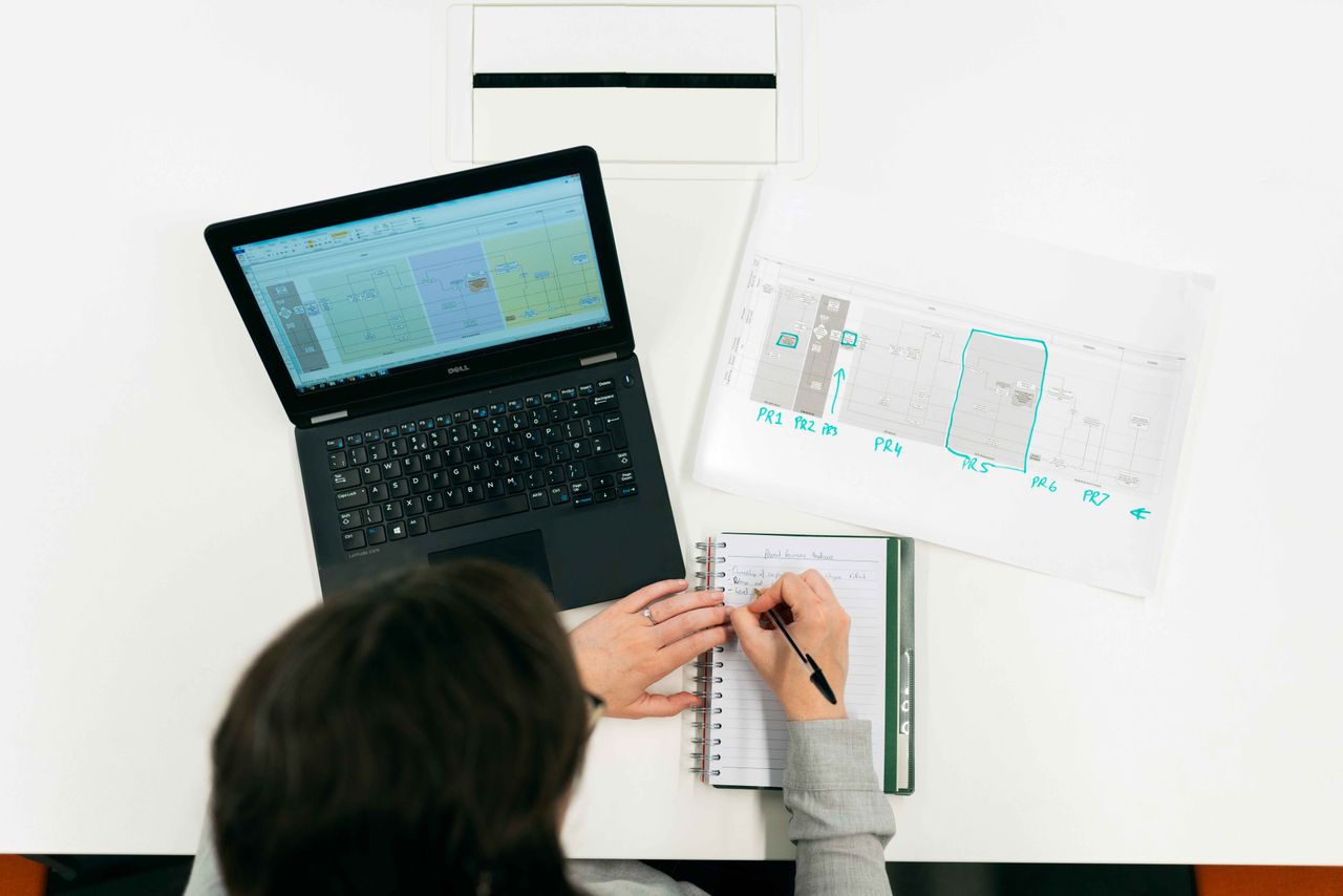 The Art of Drawing Readers In: Your attractive post title goes here A person working on a laptop, making notes from digital data and charts in an office setting.