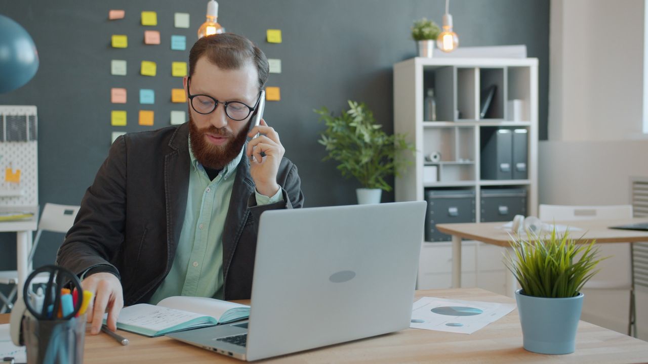 our-story Professional businessman on a phone call working in a modern office setting.